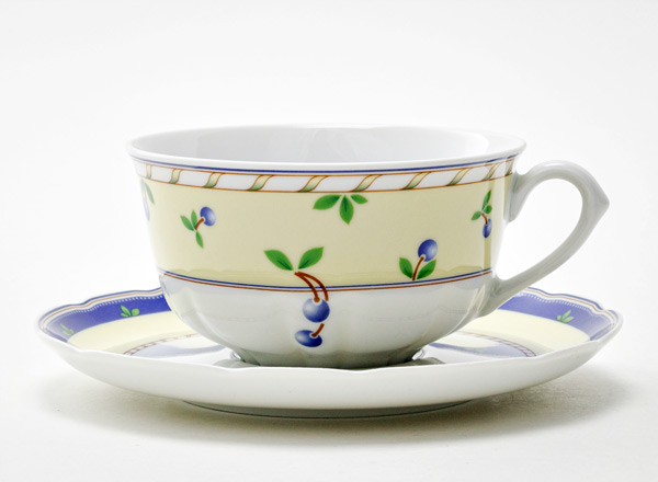 Cup and saucer tea Small berries on a pale yellow background Rose